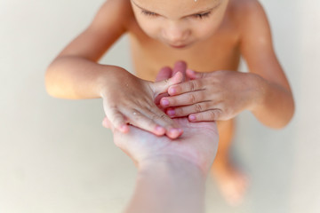 Naklejka premium A small child on the beach plays with his mother's hand. A story of trust and love.