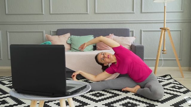 Sporty Woman Exercising While Watching Online Training on a Laptop at Home. Healthy Lifestyle Concept