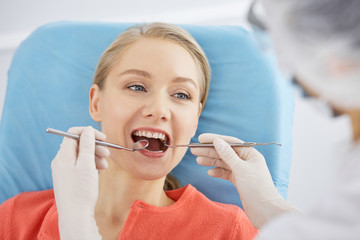 Smiling caucasian woman is being examined by dentist at dental clinic. Healthy teeth and medicine, stomatology concept