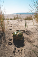 Green antique army flask washed up on shore beach laying in dunes in Ouddorp, Netherlands