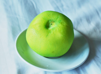 green round whole guava on a white plate