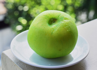 green round whole guava on a white plate