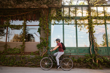 Young caucasian cyclist with helmet and sunglasses on a bicycle in front of the window