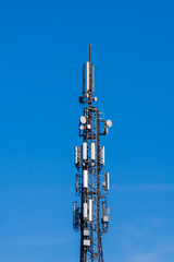 Telecommunication tower with cellular network antenna against blue sky as background