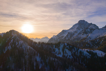 sun behind thin clouds on snowy mountains of dolomites