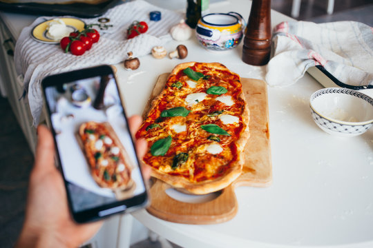 Selective focus on fresh homemade delicious pizza on kitchen counter. Food blogger make photo or video for social media of dish to share recipe for online workshop or class
