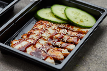 Sliced smoked eel fillet with cucumber in plastic box ready for delivery