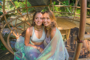 beautiful and happy girlfriends after outdoors yoga workout - two young pretty women smiling cheerful enjoying tropical jungle after fitness drill in friendship