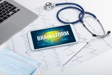 Tablet pc and medical tools with BRAINSTORM inscription, social distancing concept