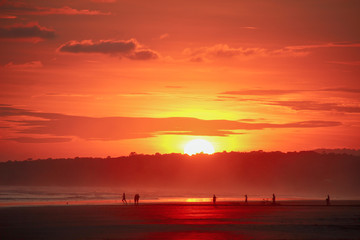 Fototapeta premium Silohuettes playing soccer on the beach before a striking sunset