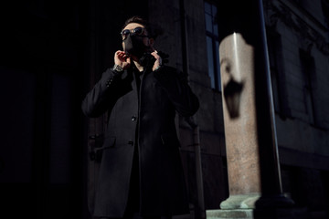  man in a black suit and a black medical mask walks through the city's historic streets during the quarantine