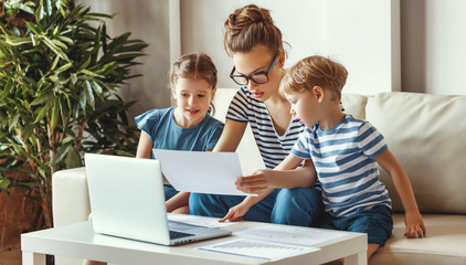 Busy woman working at home with kids sitting nearby.