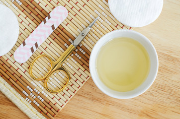 Small white bowl with olive oil, scissors and nail file. Organic nail and cuticle treatment. Natural manicure and pedicure concept. top view, copy space