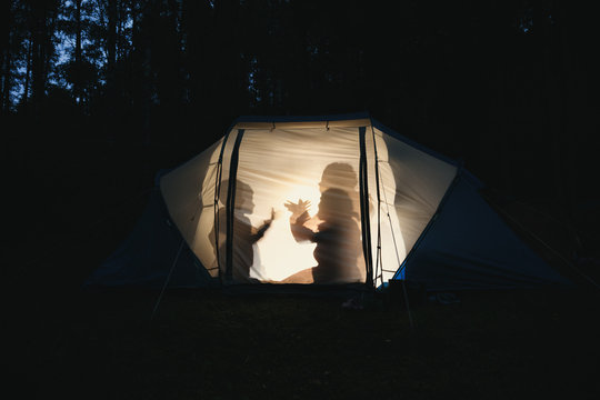 Children making shadow puppets in a camping tent at night
