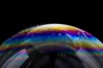 Macrophotography of a soap bubble. Multicolored streaks on the surface of the soap bubble