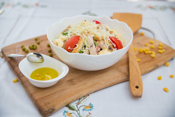 Bowl of Traditional Caesar Salad with Chicken and Bacon . Chicken Fillet and Parmesan Cheese . Peas. Corn kernels. olives on a small white bowl . Caesar salad on table - Healthy food style .