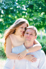 Fototapeta premium Young couple - girl huggs guy from back and smiling