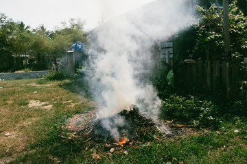 Fototapeta na wymiar A burning fire on a meadow next to a shed with lots of smoke and fumes
