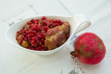 The Living Pomegranate is on a white tablecloth . Roasted pomegranet seeds . Baked pomegranate seeds and chicken .