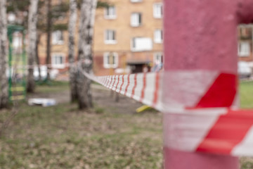 A white and red ribbon prohibits entry to the Playground. Playground swing in the open air...