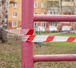 A white and red ribbon prohibits entry to the Playground. Playground swing in the open air...