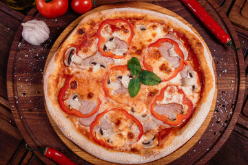 Appetizing pizza with peppers, mushrooms and ham on wooden background