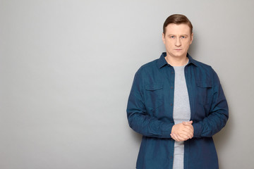 Portrait of serious focused man holding hands folded together