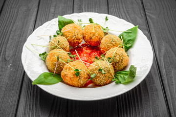 fried meat balls with vegetables and sauce on a plate