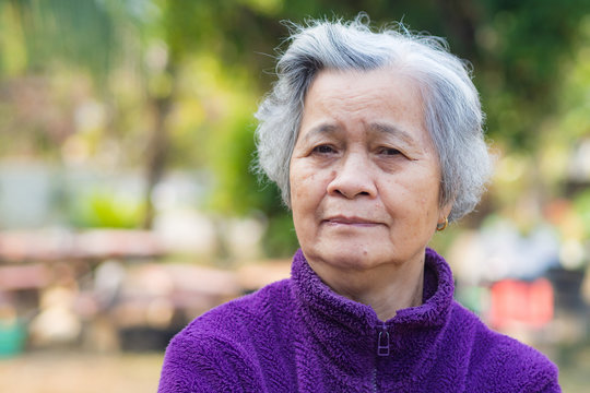 A portrait of an elderly woman smiling and looking at the camera while standing in a garden. Asian old woman healthy and have positive thoughts on life make her happy every day. Health care concept