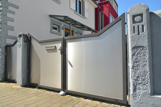Metalltor in der Einfriedung im Zugangsbereich vor einem Einfamilienhaus