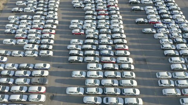 Aerial view of new cars lined up on manufacture parking lot. Flying backwards.