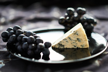 A piece of blue cheese is on a black plate.