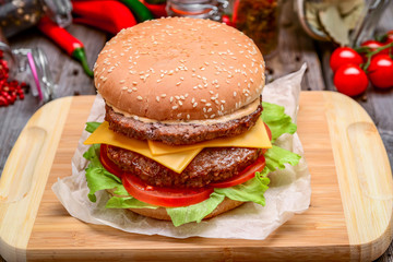 big cheeseburger with melted cheese and on wooden background