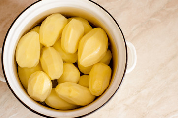 Raw peeled potatoes in a pot of water, prepared for cooking. The view from the top.