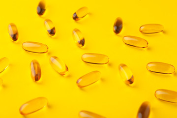 Close-up gold fish oil softgel fatty acid capsules scattered