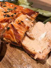 Ready-made baked and rosy soufflé of salmon fillet, decorated with sprigs of thyme, next to them are pickled cucumbers, are on a wooden board on the table