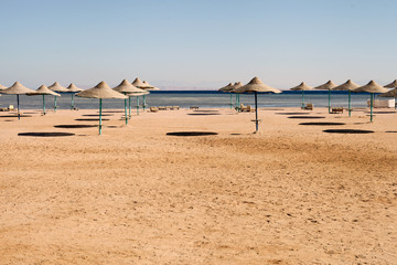 empty beach at summer time. empty matching umbrellas on a beach, blue skies in the distant view. Horizontal with copy space.