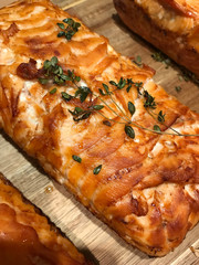 ready-made baked and ruddy salmon fillet souffle decorated with thyme sprigs lies on a wooden board on a table to prepare for serving