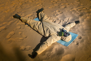 man in protective suit, mask on sand