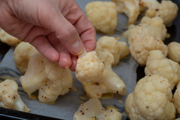 Oven baked spicy cauliflower on a black metal background.
