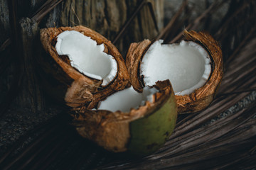 Broken coconuts on a wooden table with palm leaves