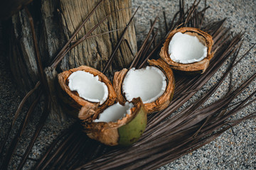 Obraz na płótnie Canvas Broken coconuts on a wooden table with palm leaves