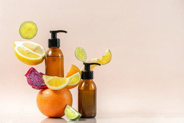 Glass bottles with bodycare and skincare soap or lotion near fruits
