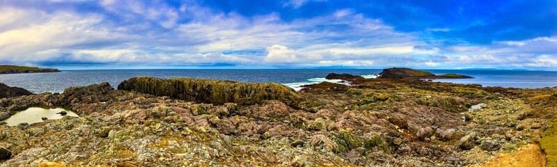 Fototapeta na wymiar Inishbofin Island ultra wide panorama on the rocks, atlantic ocean and blue sky with clouds