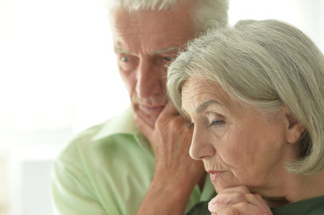 Portrait of sad senior couple posing at home