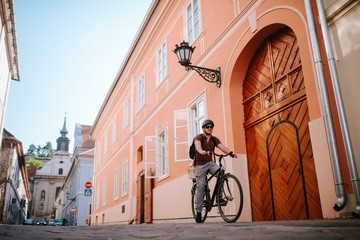 Fototapeta premium Handsome young caucasian man riding a bicycle by the house