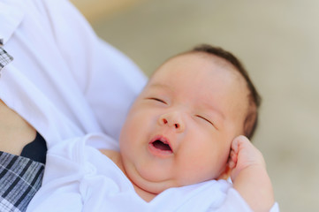 Asian woman holding a newborn baby in her arms at home.Mother day and newborn baby infant health care concept.