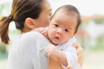 Asian woman holding a newborn baby in her arms at home.Mother day and newborn baby infant health care concept.