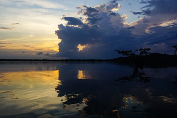 Fototapeta na wymiar CUYABENO WILDWIFE RESERVE, ECUADOR - DECEMBER 14, 2019: Reflections of the clouds coloured from the sunset in Lake Cuyabeno 