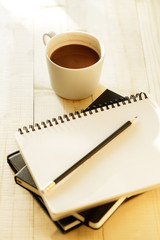 cup of hot chocolate on wooden background with notebook.  Work from home concept.